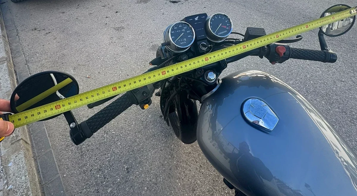 Midiendo con una cinta la separación entre los retrovisores de una moto